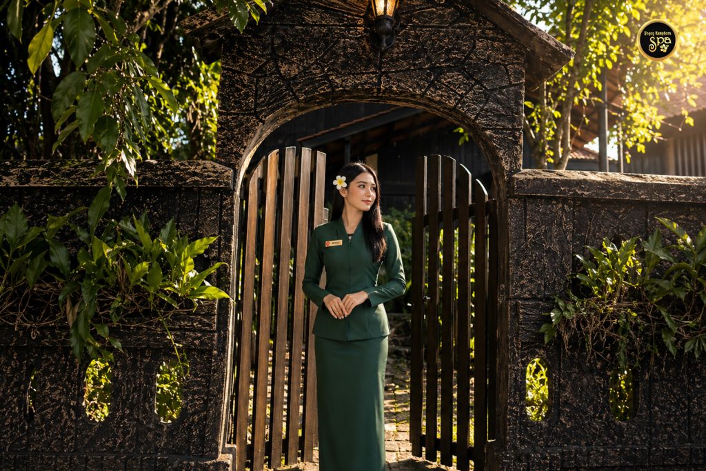 Spa therapist standing at traditional entrance of Yoyoy Kamphora Spa Cherating