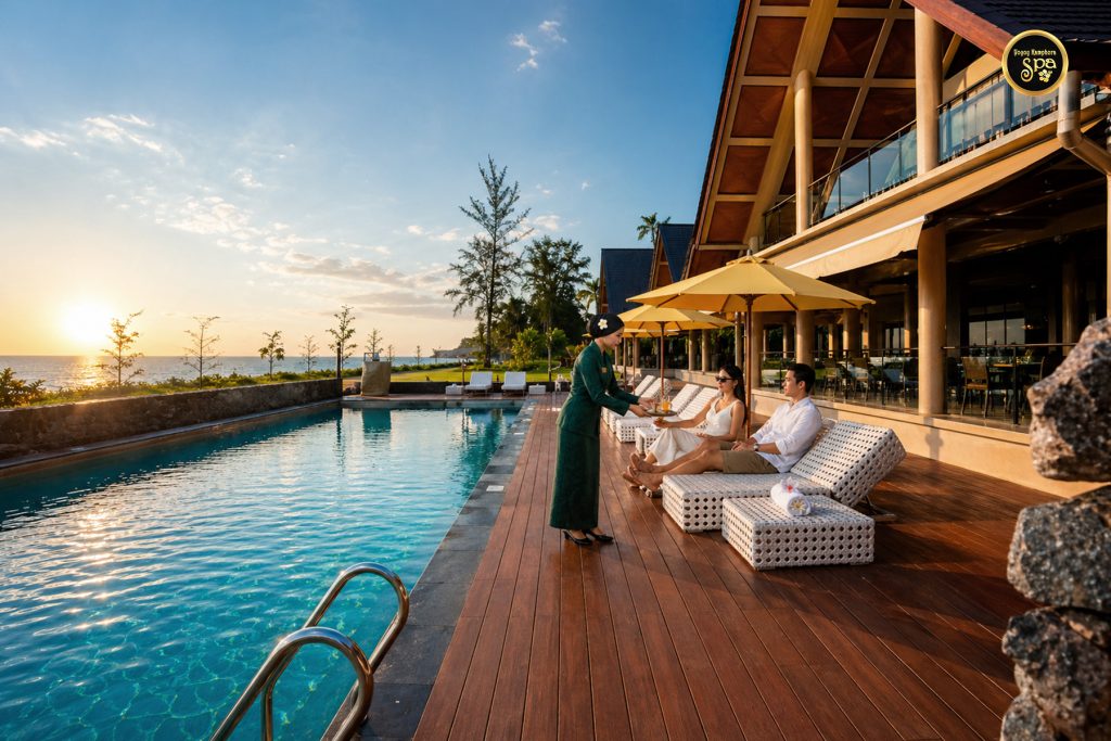 Spa therapist serving tea to guests by luxury pool at beach resort spa Malaysia