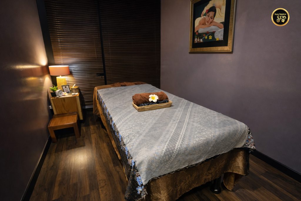 Single spa treatment room with massage bed and warm lighting at Yoyoy Kamphora Spa